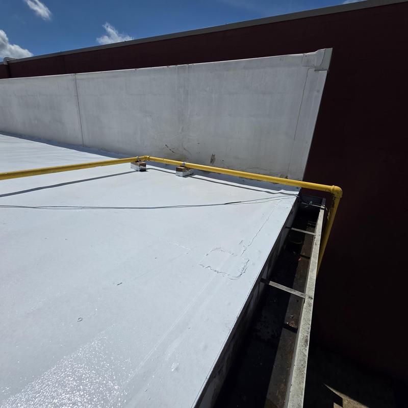 Silicone roof restoration with yellow gas pipe guards