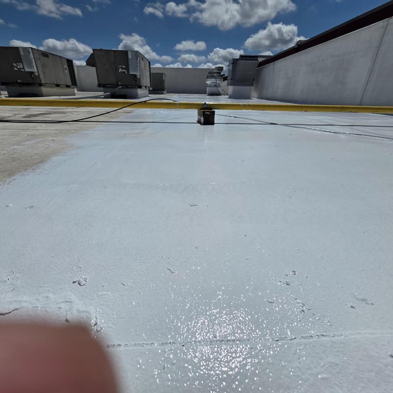 Silicone roof restoration with rooftop HVAC units under blue sky