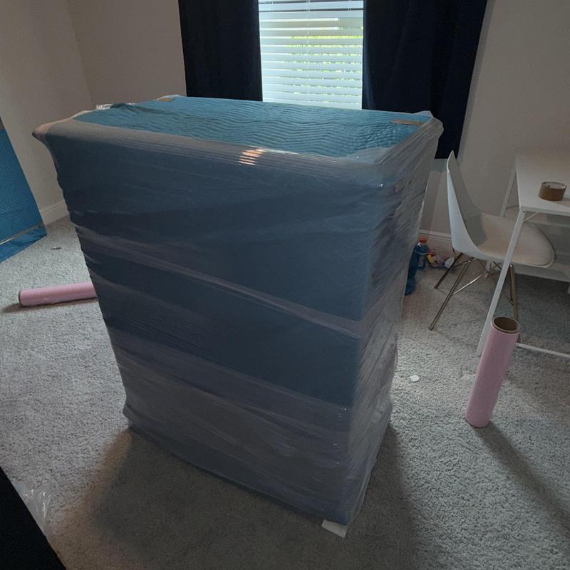 Furniture wrapped in protective moving blanket in home