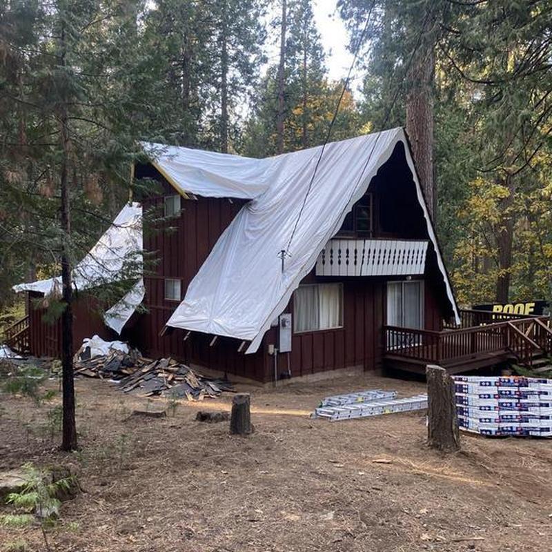 A-frame cabin roof covered with tarp in forest
