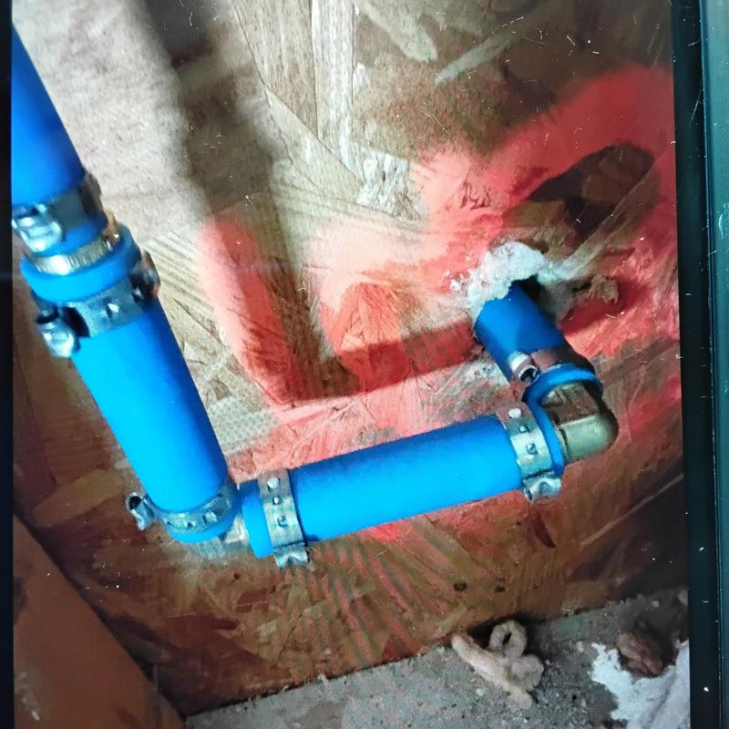 Blue PEX water lines with clamps installed in wall cavity