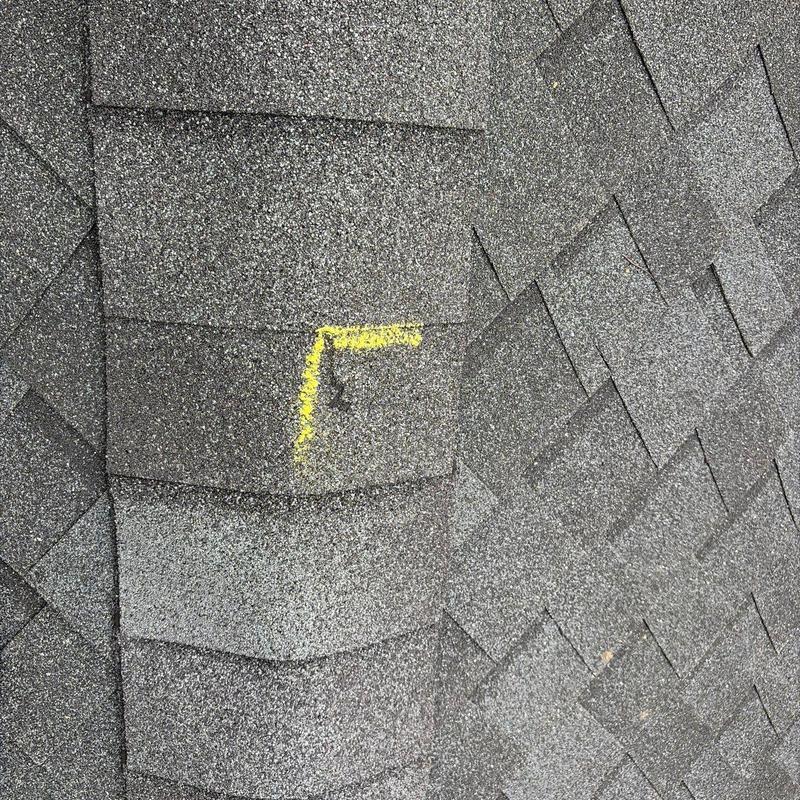 Roof shingles with hail damage marked in yellow paint