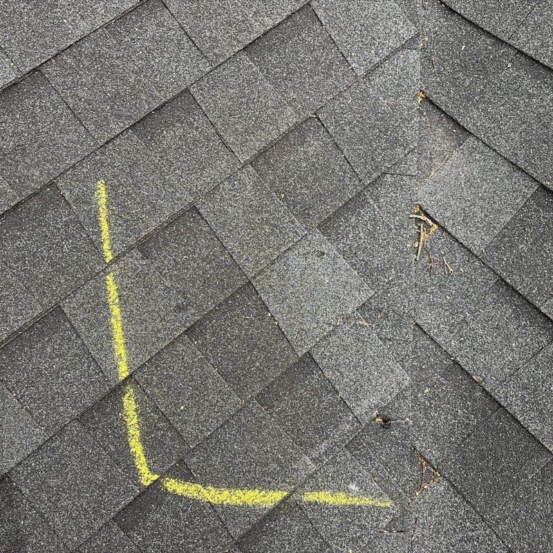 Asphalt shingles with hail damage marked in yellow