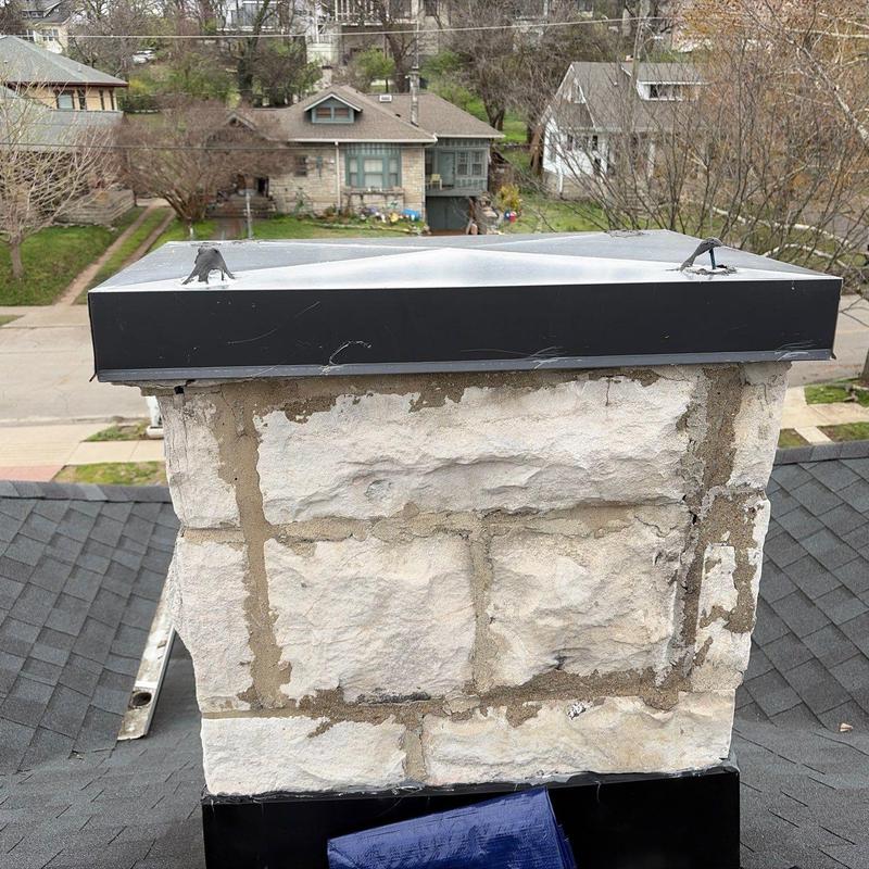 Chimney stone masonry with metal cap on roof
