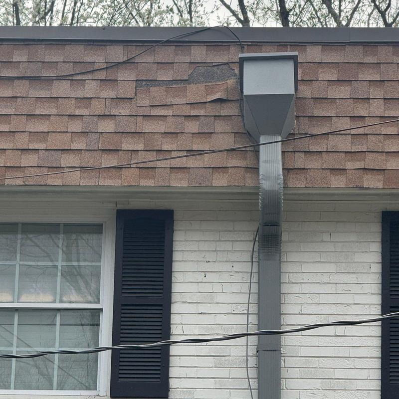 Roof shingles with visible hail damage near gutter system