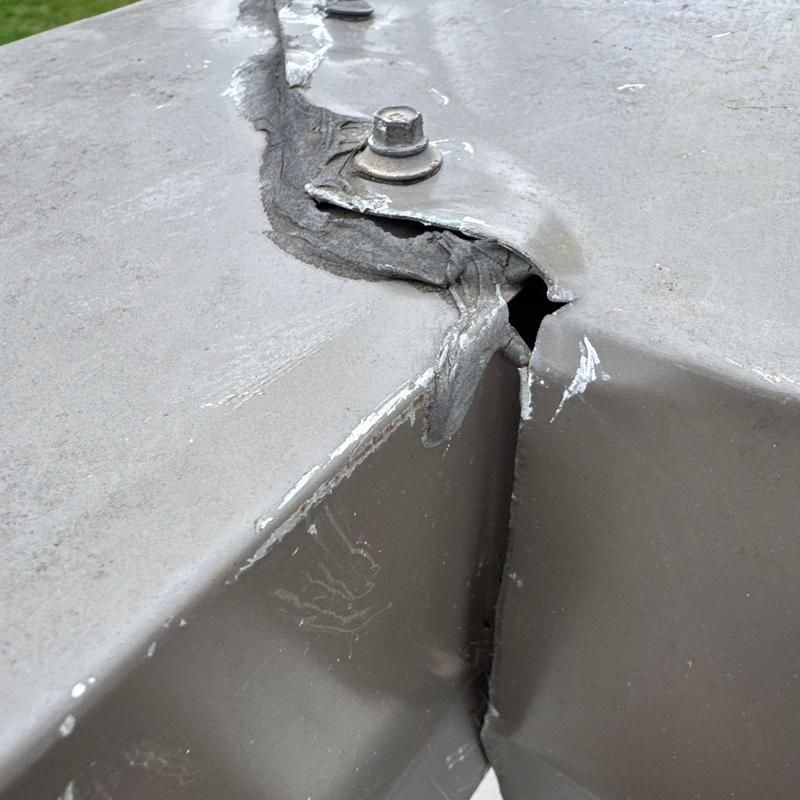 Metal roof flashing with cracked sealant and bolt