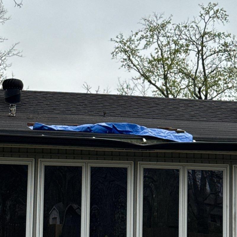 Shingles and roof vents with tarp covering damage