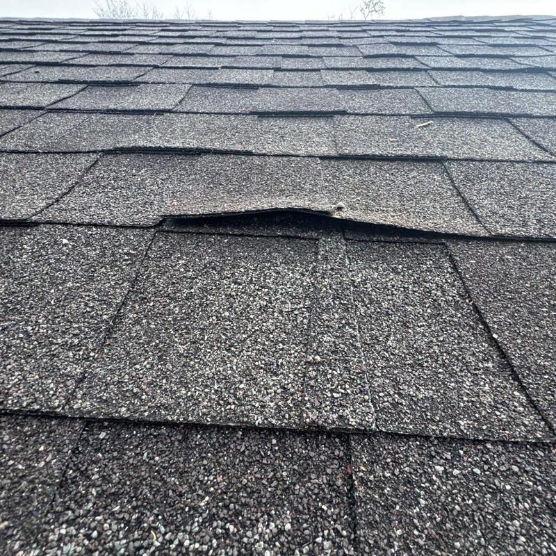 Asphalt shingles with hail damage and lifting edges