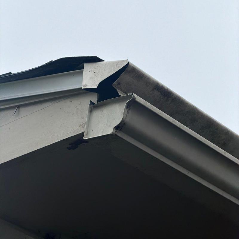 Metal gutter with separated corner joint on roof edge