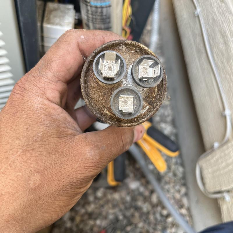 HVAC start capacitor held in hand for inspection HVAC start capacitor held in hand for inspection