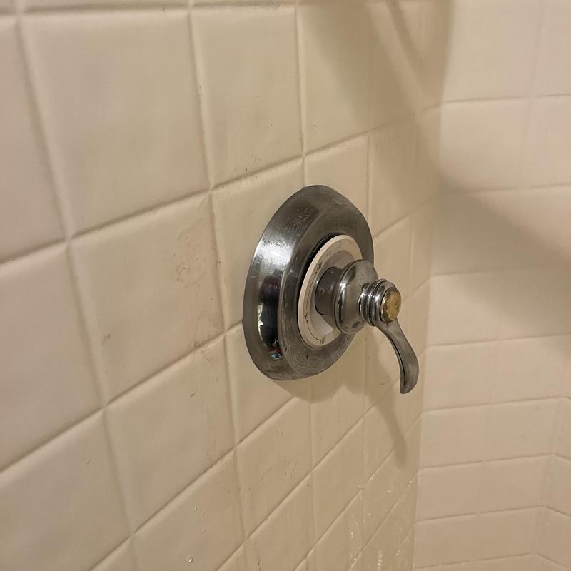 Shower valve handle on white tiled wall Shower valve handle on white tiled wall