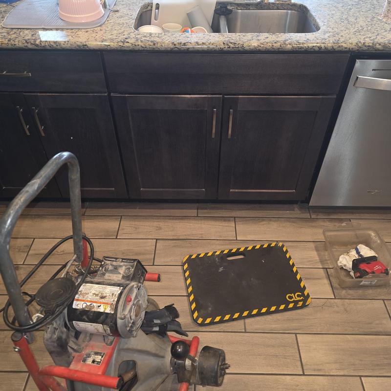 Kitchen sink drain with drain snake and tools on floor
