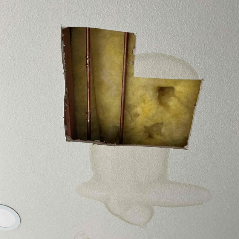 Copper water pipes inside ceiling with water damage stain