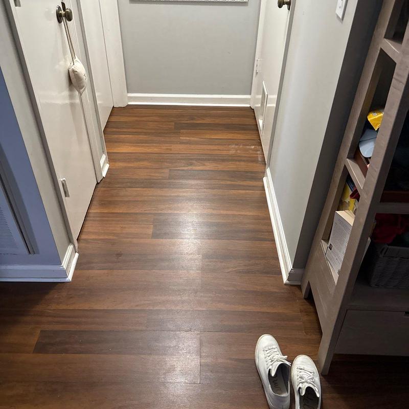 Wood laminate flooring in hallway near shelving unit