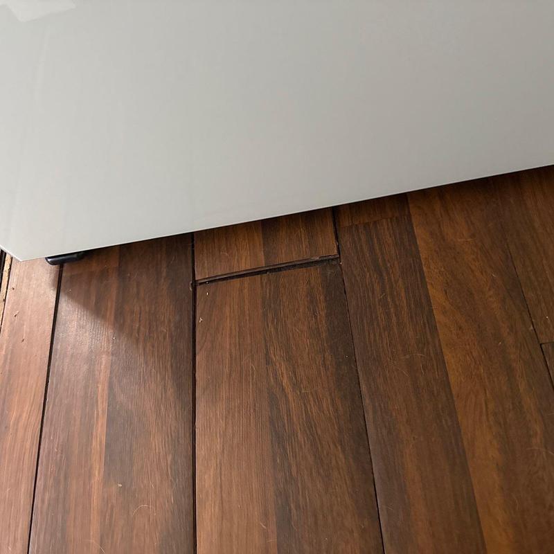 Wood floor planks with lifting and gaps near wall panel