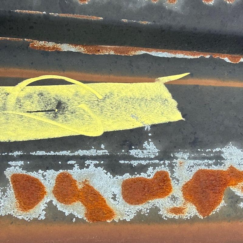 Metal roofing panel corrosion and rust spots marked with paint