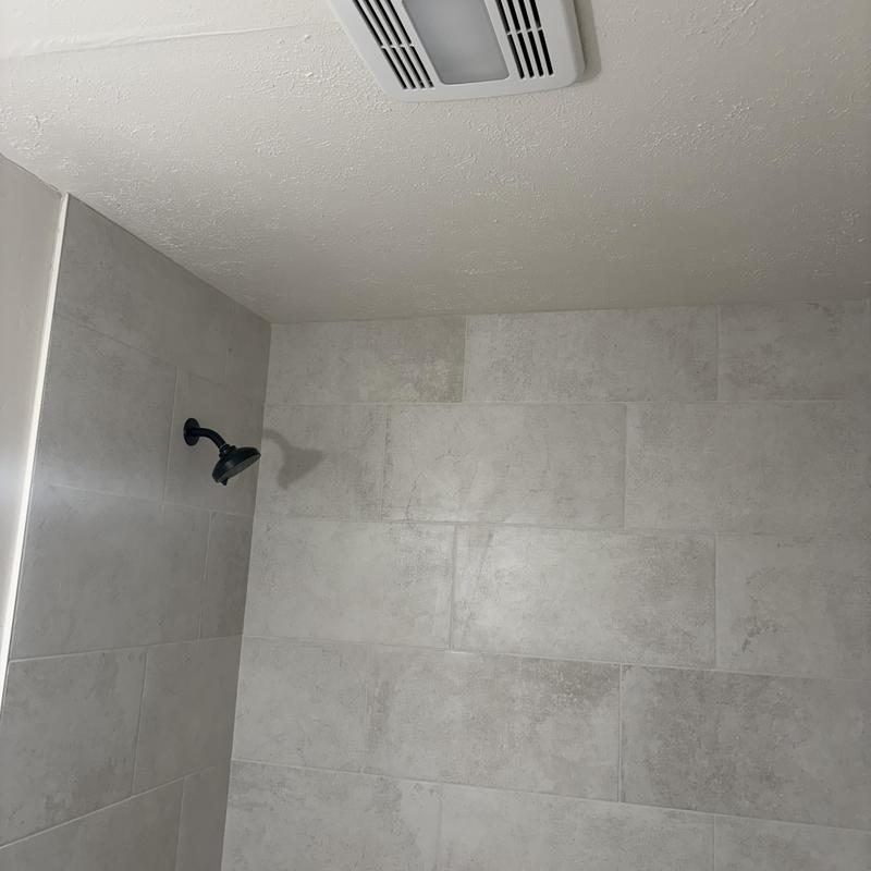 Bathroom exhaust fan ceiling vent installed in tiled shower room