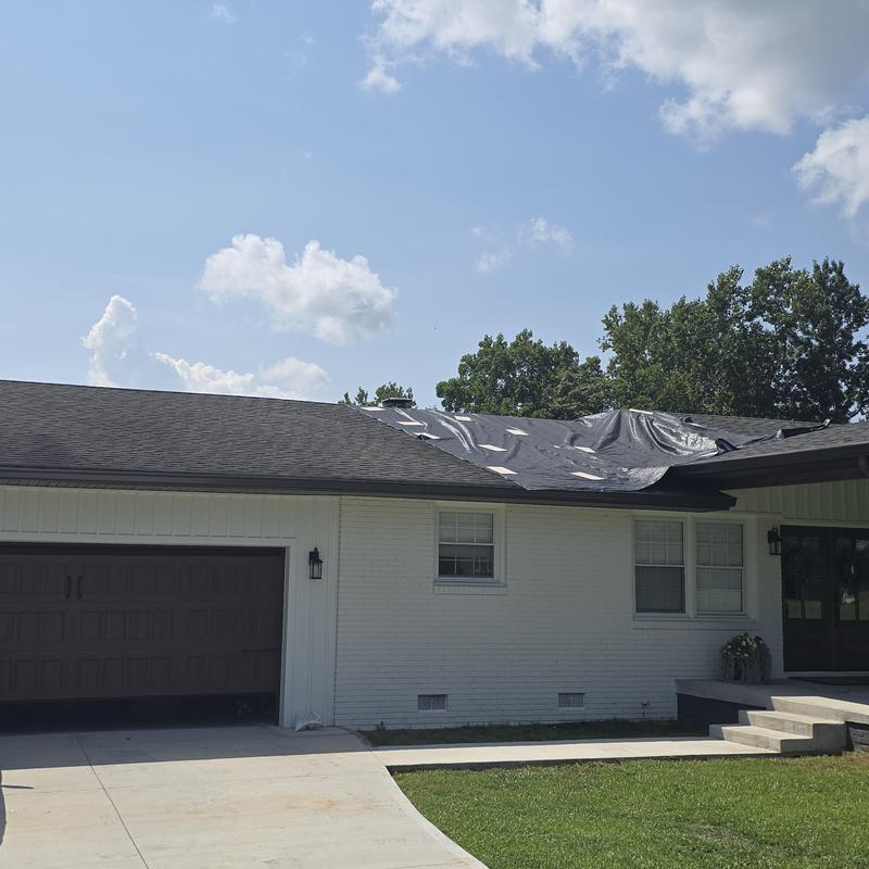 Shingle roof with tarp covering leak area