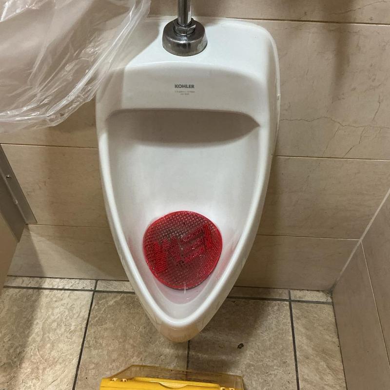 Urinal flushing system with red urinal screen installed Urinal flushing system with red urinal screen installed