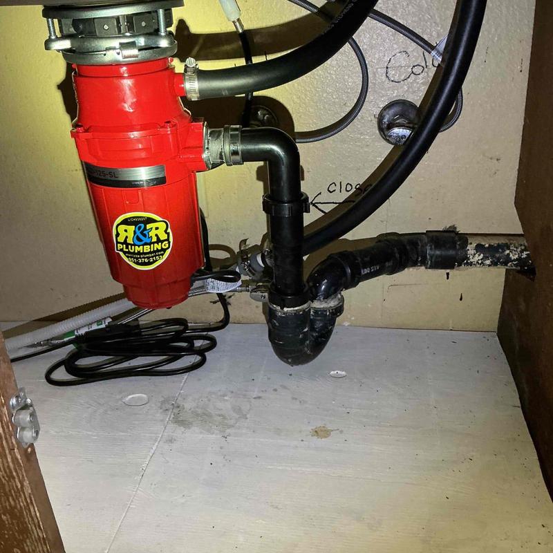 Garbage disposal installation with drainage piping under sink