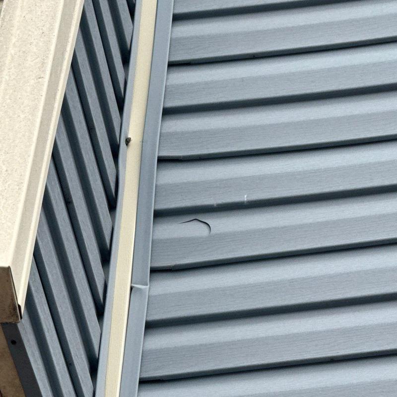 Metal roofing panel with hail damage near trim edge