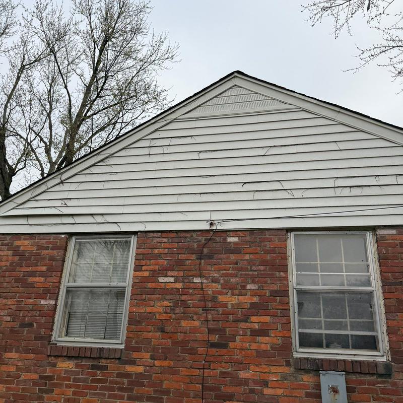 Vinyl siding with visible hail damage on house exterior