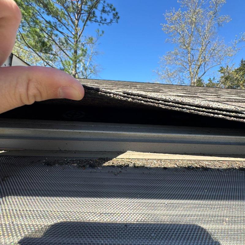 Asphalt shingles lifted for inspection on roof edge