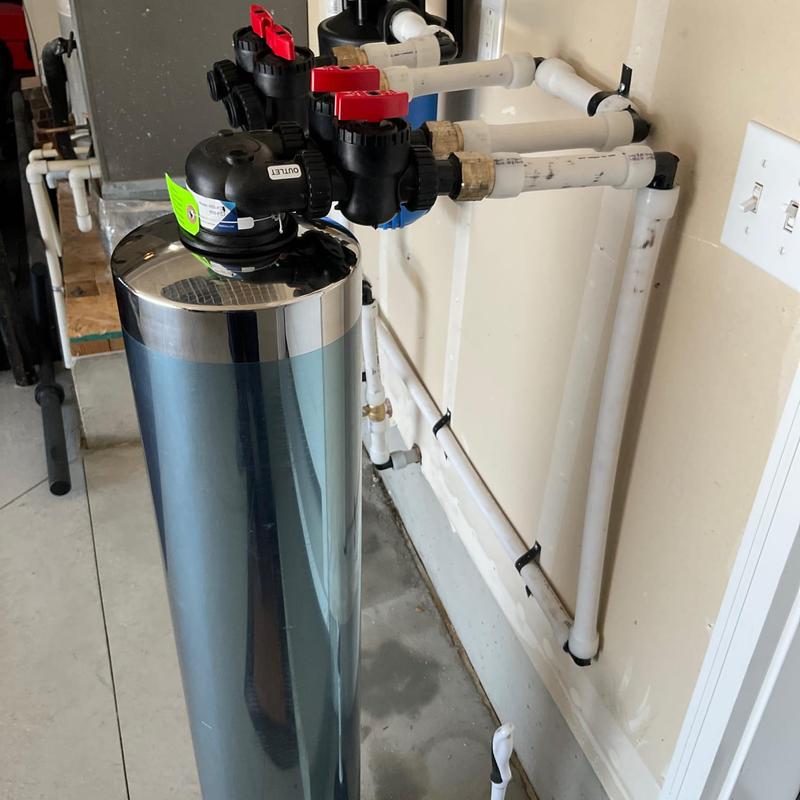 Water softener system with PVC pipe connections in garage