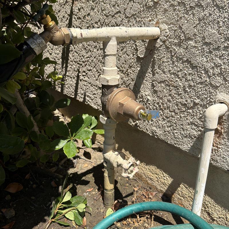 Water pressure regulator and hose bib on home exterior