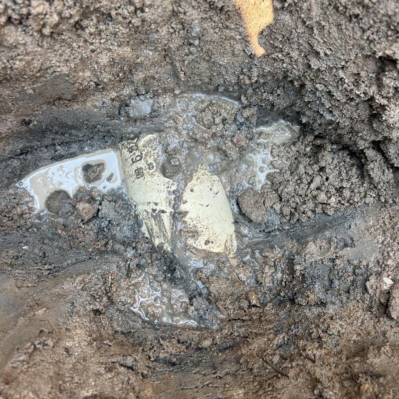 Septic drain field excavation with exposed pipe and soil