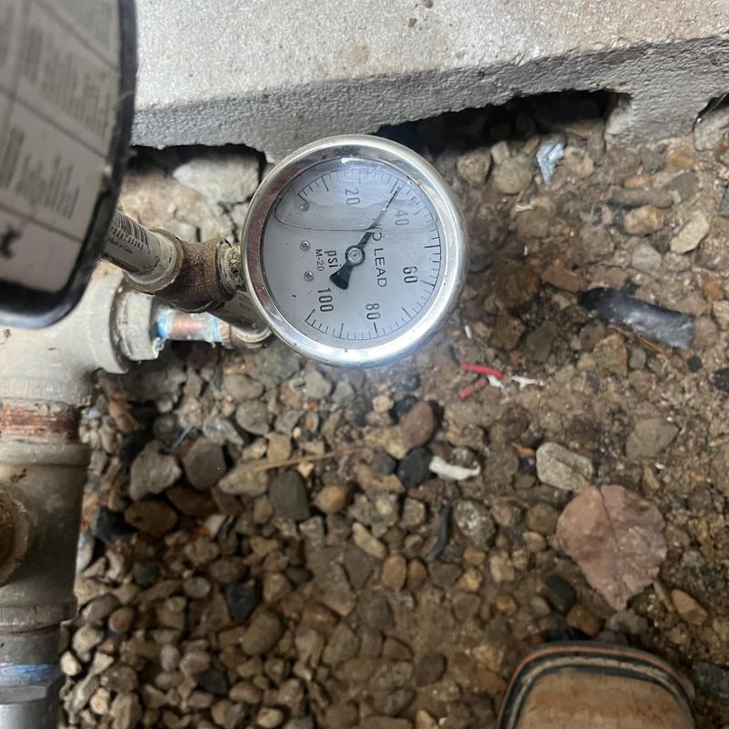 Well pump pressure gauge on gravel floor near broken concrete Well pump pressure gauge on gravel floor near broken concrete