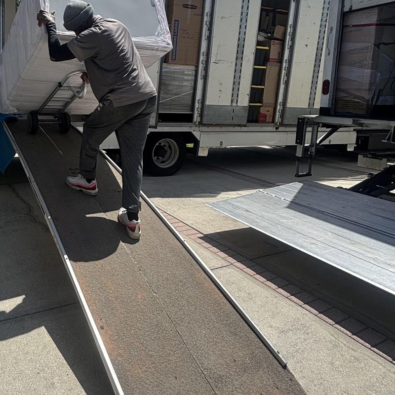 Wrapped dining room set loaded onto moving truck ramp