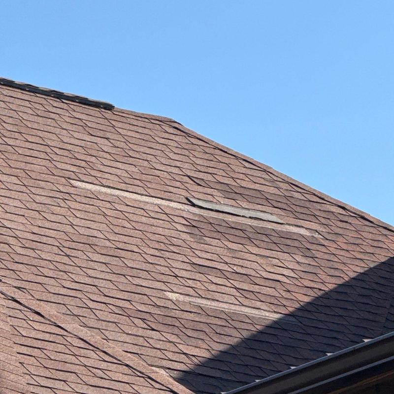 Asphalt shingle roof with hail damage and lifted shingles