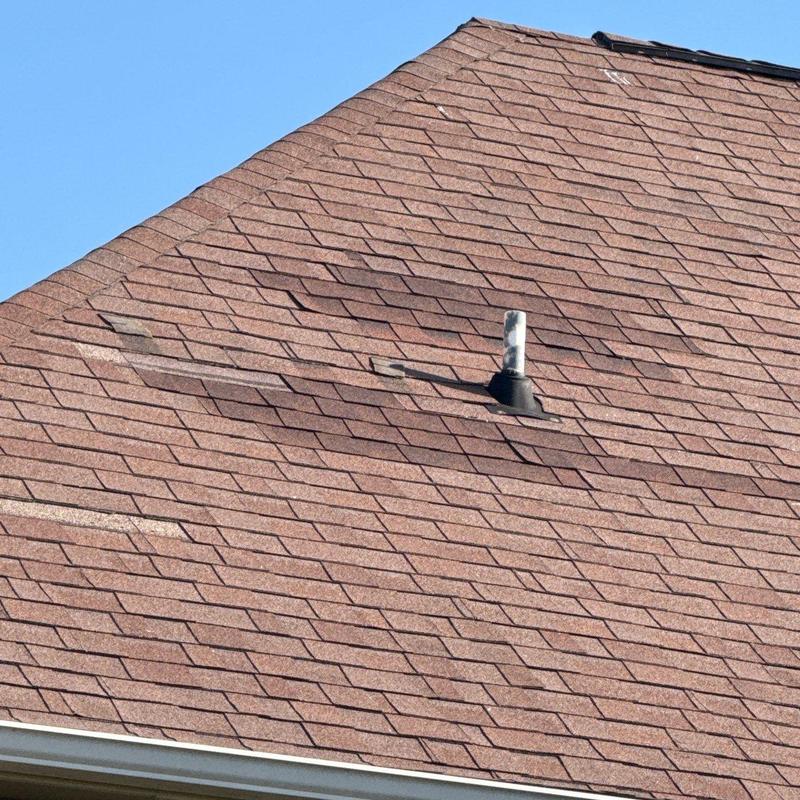Asphalt shingle roof with hail damage near vent pipe