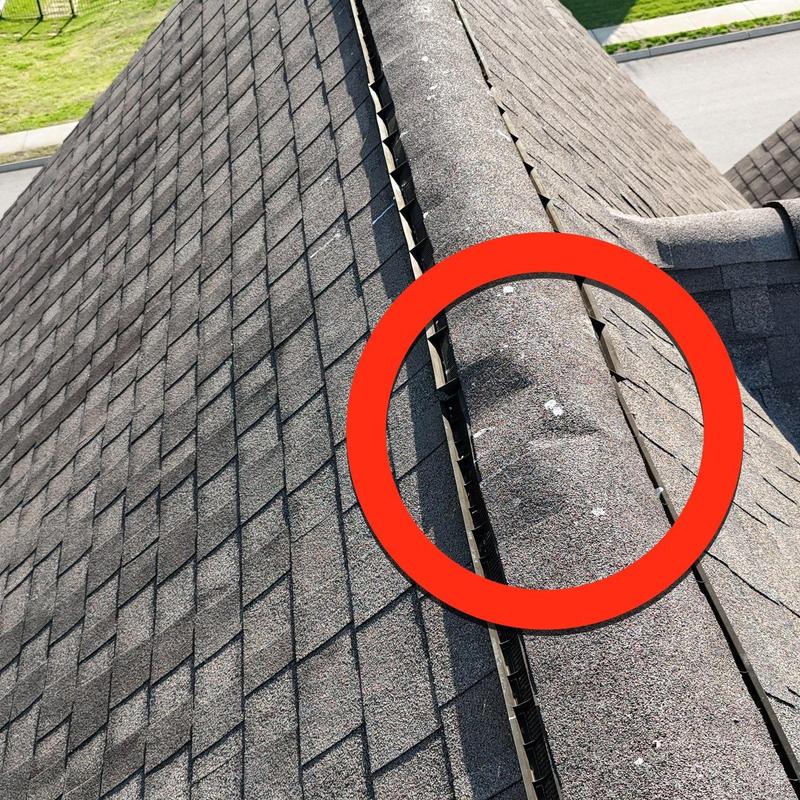 Roof ridge cap with hail damage near flashing