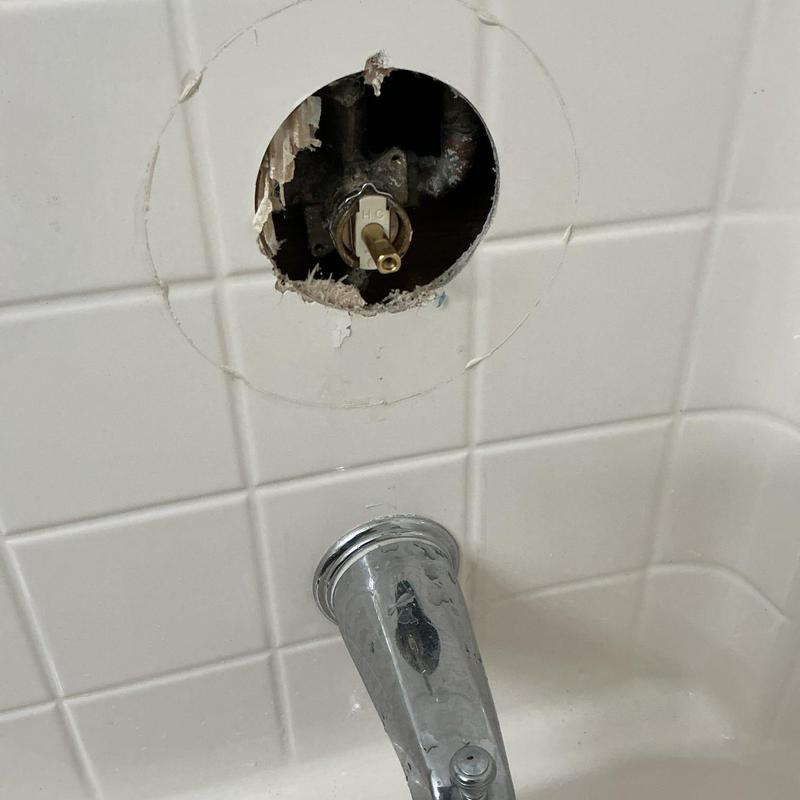 Shower cartridge valve exposed in bathroom tile wall