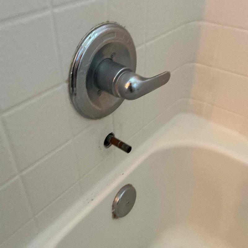 Bathtub diverter valve removed, wall tile and tub visible