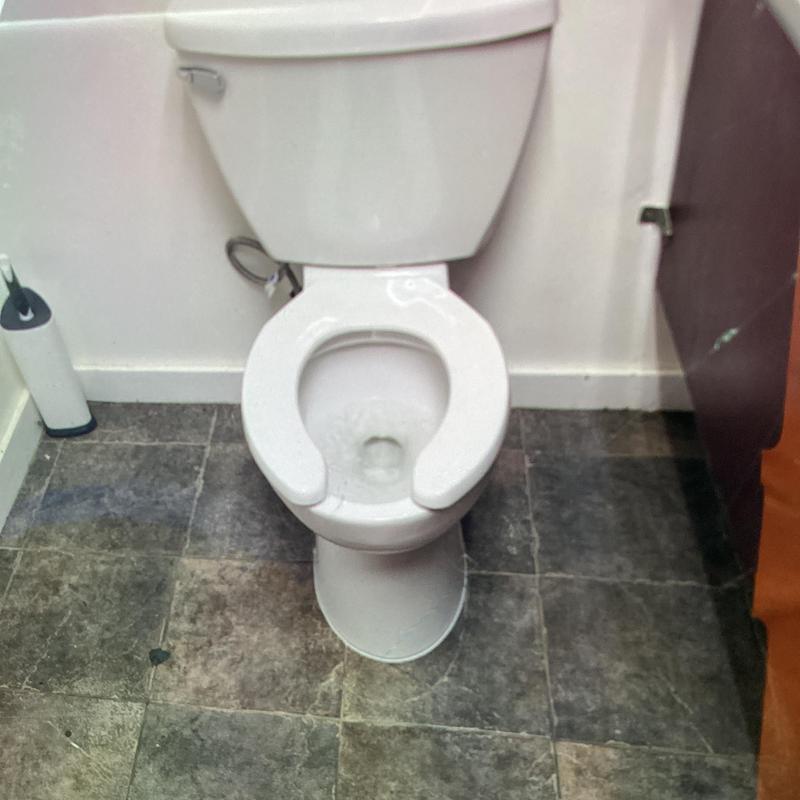 Power flush toilet with secured flange installed in bathroom stall