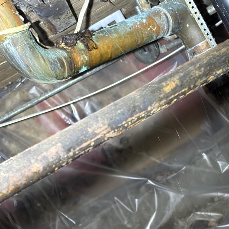 Cast-iron plumbing pipe with corrosion and leak in crawlspace Cast-iron plumbing pipe with corrosion and leak in crawlspace