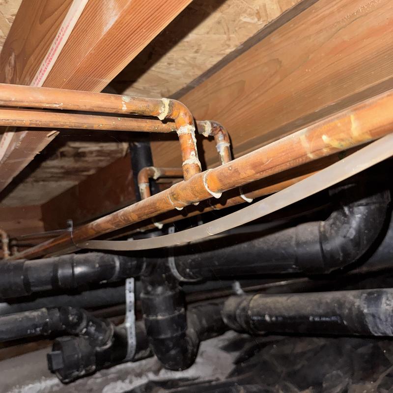 Corroded copper water pipes and plumbing in crawlspace