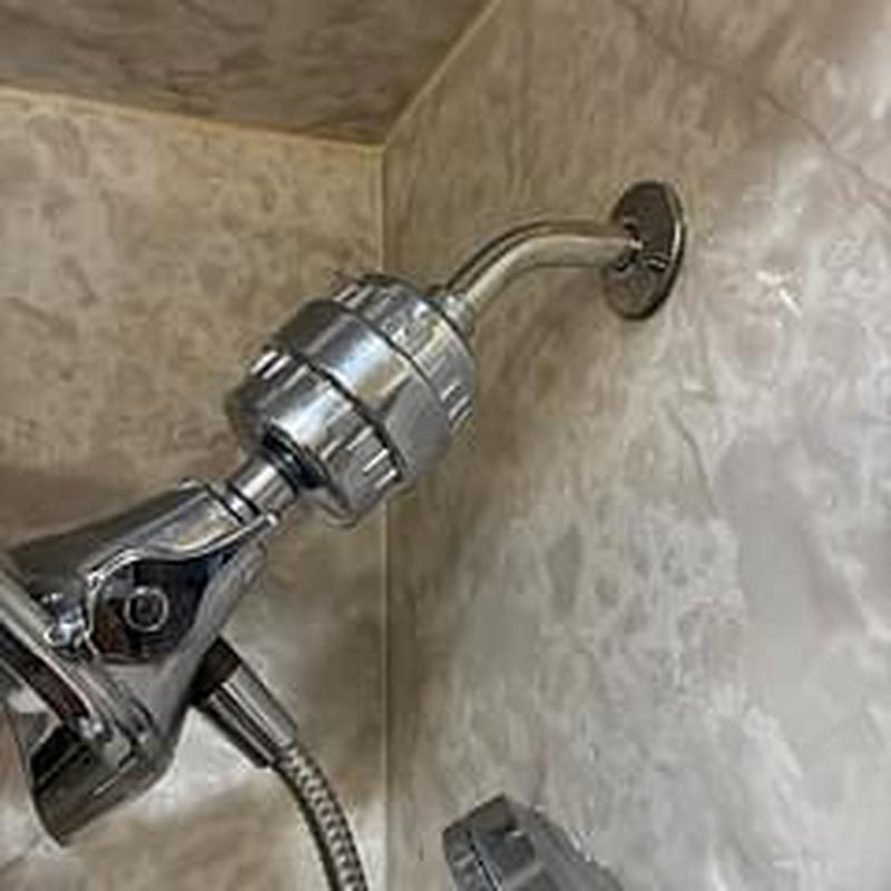 Shower arm with attached shower head in bathroom wall Shower arm with attached shower head in bathroom wall