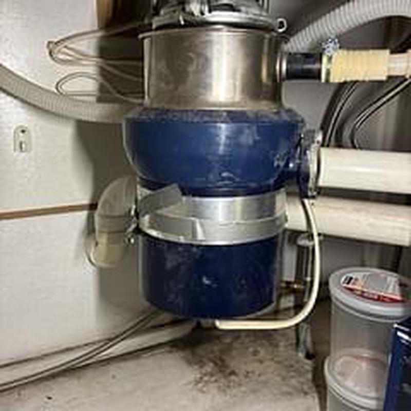 Garbage disposer under kitchen sink with plumbing connections Garbage disposer under kitchen sink with plumbing connections