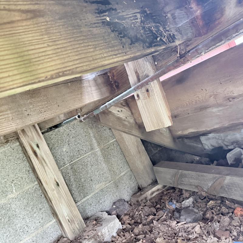 Copper water pipe leaking under wooden floor joists in crawl space
