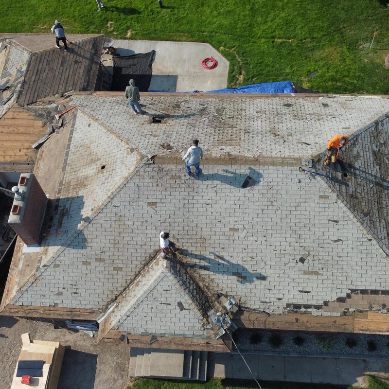 Asphalt shingle roof tear-off with workers on site Asphalt shingle roof tear-off with workers on site