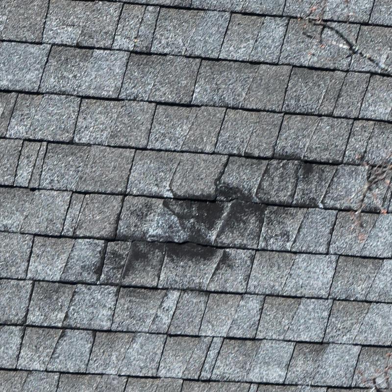 Asphalt roof shingles with hail damage patch