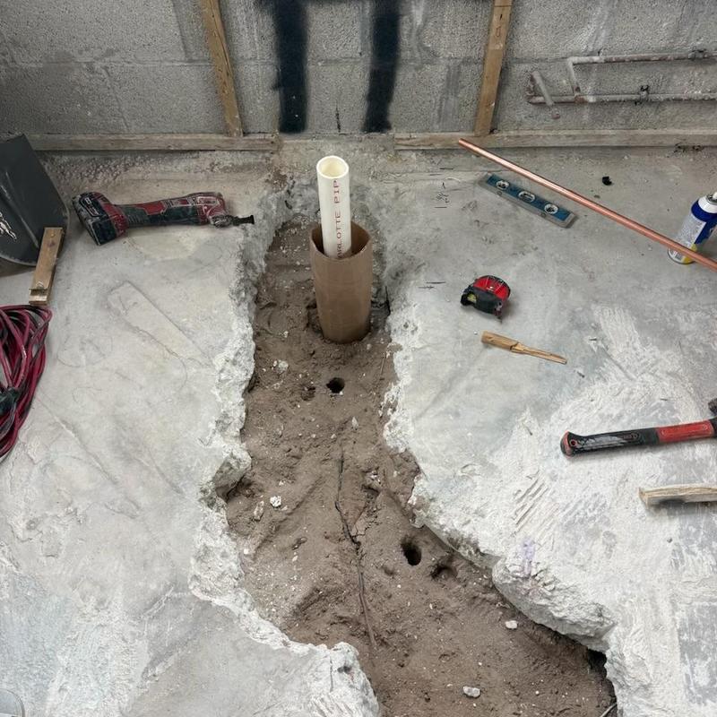 Shower drain plumbing trench with PVC pipe installation
