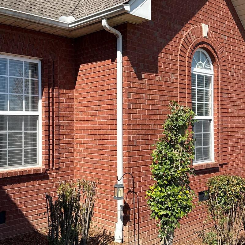 Gutter downspout and brick exterior with windows