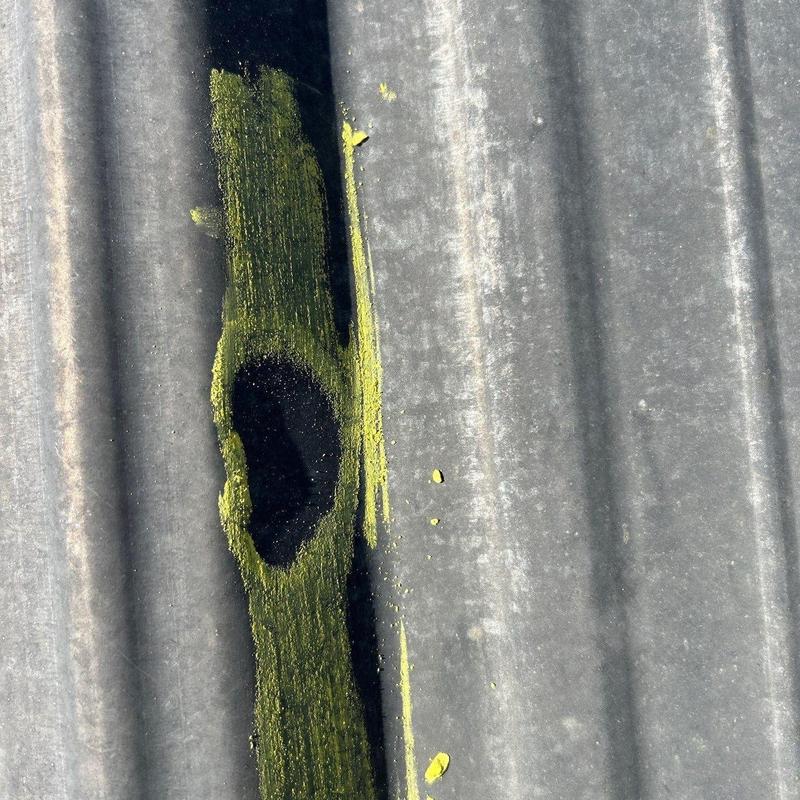 Metal roof panel hail damage marked in yellow paint