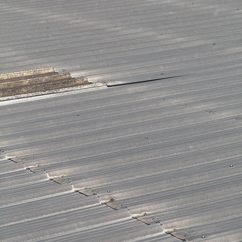 Metal roof panels with cracked and damaged sections