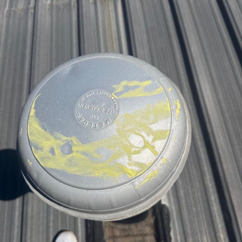 Metal roof gas vent with yellow hail damage marks